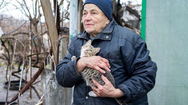 Vira holding her cat standing in her front yard